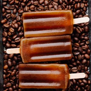Close up of three brown coffee popsicles on a backdrop of coffee beans