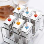 Six stainless steel popsicle molds with a lid on it and a wooden popsicle stick in each mold