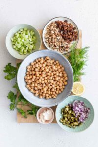 Ingredients for Chickpea Salad Sandwich on a wooden cutting board in bowls
