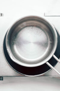 A stainless steel pan with water on a small silver stove.