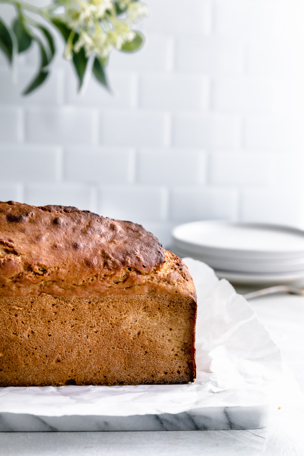 whole baked applesauce bread with a white tile kitchen background