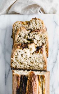 top view of three slices of banana bread on white marble backdrop