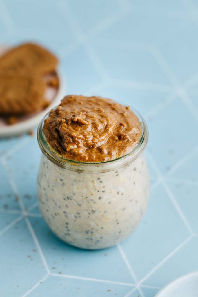 A small glass jar with overnights oats and creamy Lotus Biscoff spread as a topping.