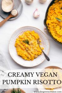 Creamy vegan pumpkin risotto in a cream-colored bowl with a fork on a white backdrop with a cast iron pan with pumpkin risotto and small bowls with ingredients and risotto
