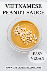 A small glass bowl on a grey backdrop with creamy peanut sauce and garnished with chopped peanuts with the text Vietnamese peanut sauce written on top and on the bottom a text saying easy vegan