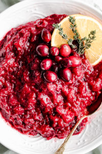 close up cranberry sauce decorated with orange slices, cranberries and thyme