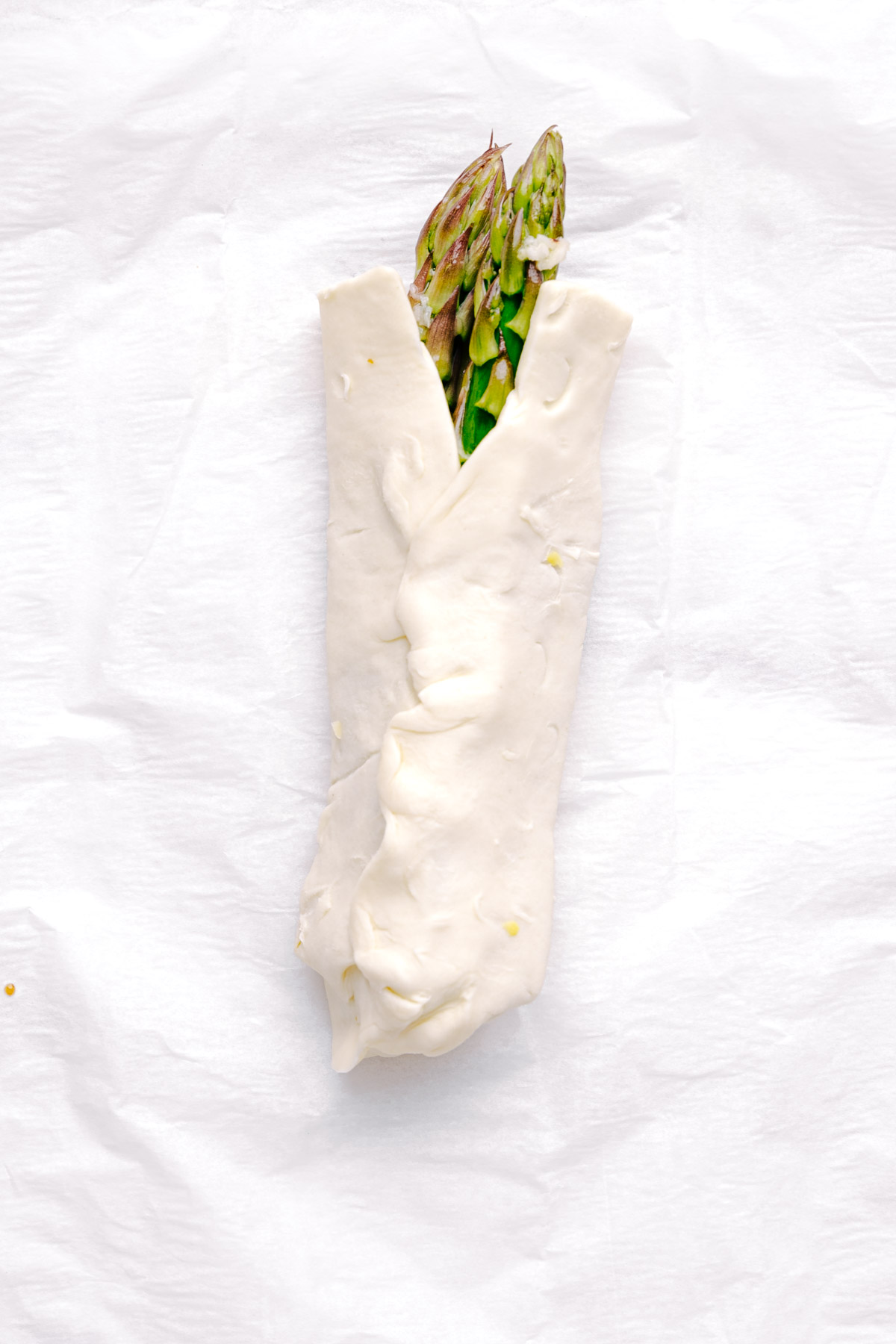 A bundle of Asparagus with Puff Pastry on white parchment paper