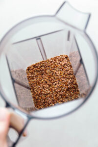 The top view of a blender with whole flaxseeds on the bottom.