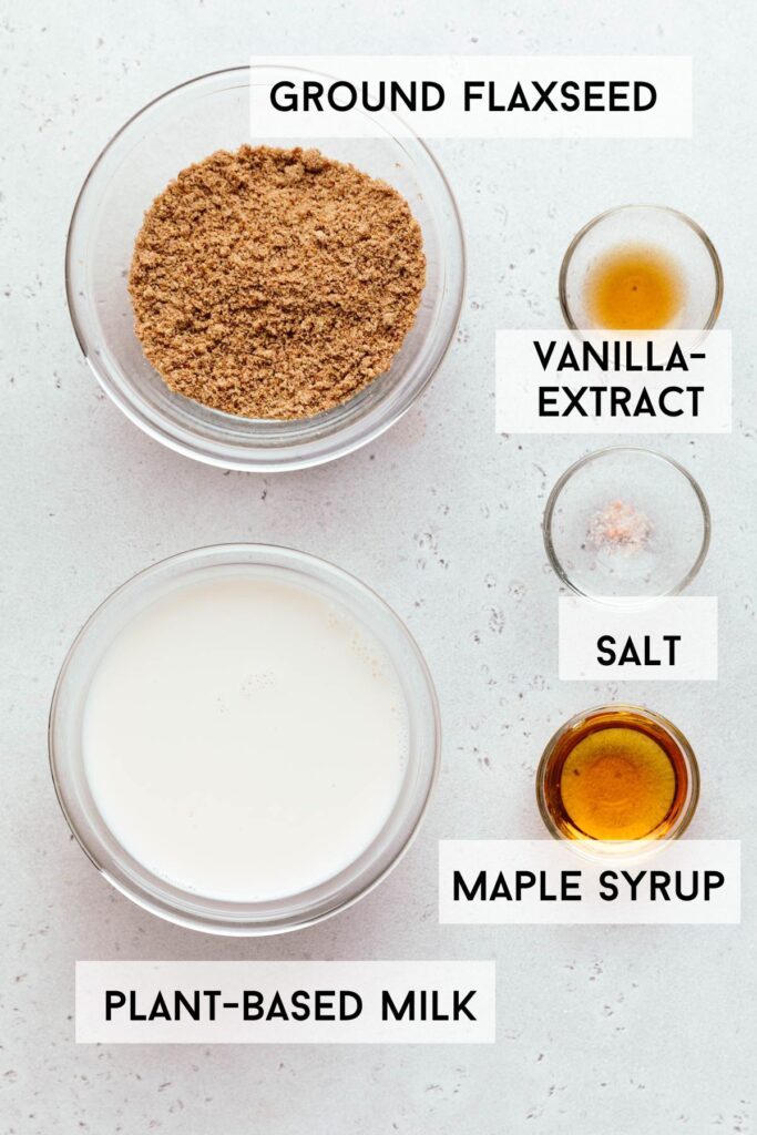 Two small bowls with ground flax seeds and white milk with smaller bowls with vanilla-extract, salt and maple syrup and a text with the ingredients in bold next to each bowl.