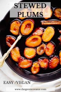 Orange and red color plum halves in a syrupy liquid with the inside facing up in a black skillet with a golden spoon with one plum halve in it and the words stewed plums in bold written on top and the words easy vegan in the bottom.