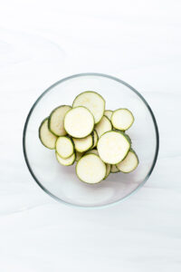 Zucchini slices in a glass bowl on a white backdrop