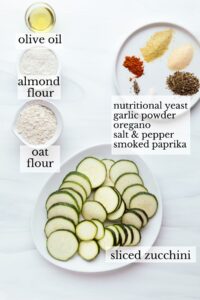 Ingredients for air fryer zucchini on white plates and and in small bowls with text next to it of the ingredients