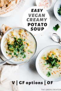 two bowls of cooked creamy potato soup with silver spoons on a white background