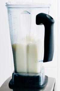 Blended ingredients for pina colada in a tall standing blender container