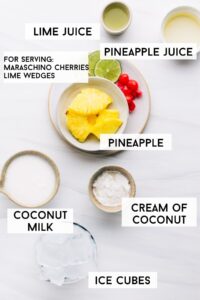 Ingredients for Piña Colada Mocktail on a white backdrop in several small bowls with text of the ingredients next to it