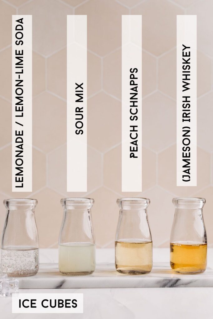 Ingredients for green tea shot in front of a tiled backdrop in several small glass bottles with descriptive labels.
