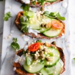 three sweet potato toast with toppings on a marble white backdrop