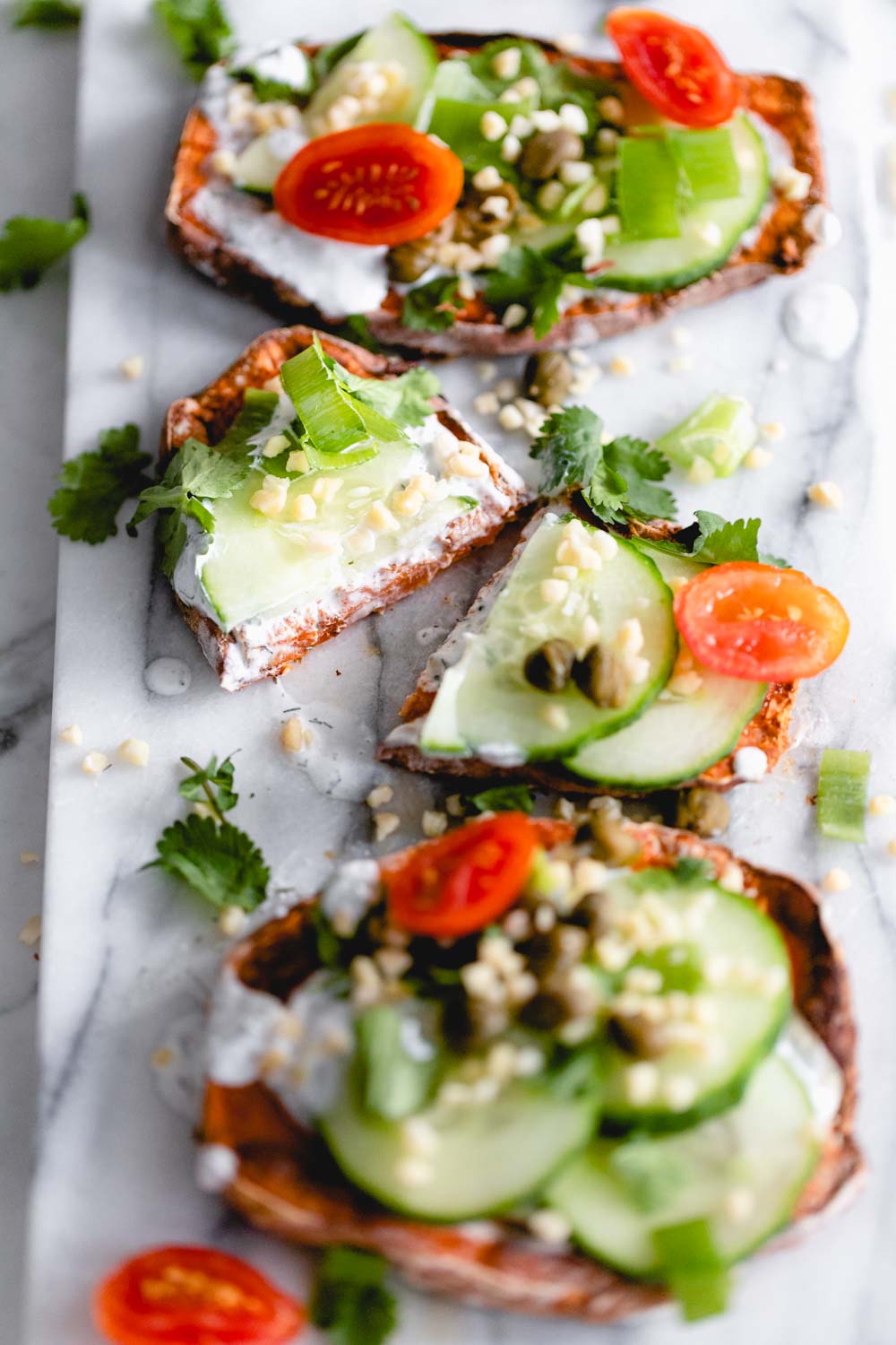 three sweet potato sweet potato toast with toppings on a marble white backdrop one toast is cut in half