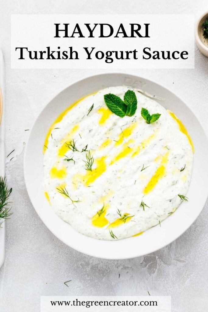 A bowl on a light grey backdrop with a thick dip in it garnished with olive oil, dill and mint leaves and the text haydari Turkish Yogurt Sauce in bold on top.