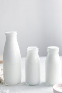 three different size glass bottles with coconut milk with white background