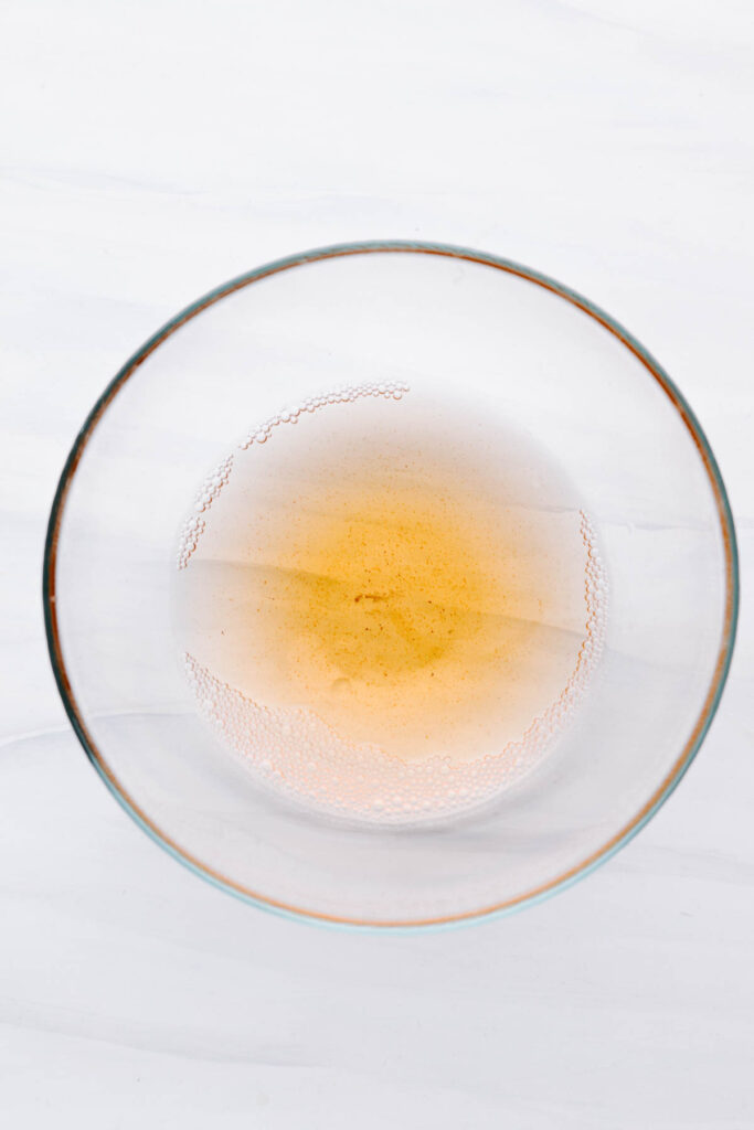 A glass bowl with water and red wine vinegar.