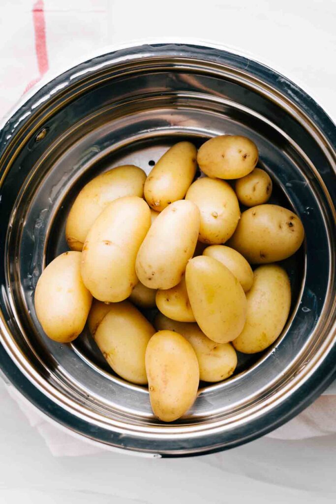 Boiled potatoes draining in a stainless steel strainer.