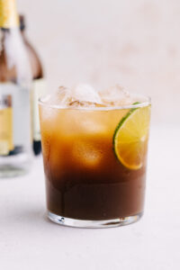 A glass with cold brew tonic with ice cubes and a slice of lime