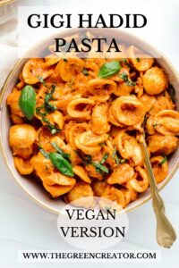 Orange colored shell pasta in a bowl sprinkled with chopped basil and a few small basil leaves with the text GIGI HADID PASTA on top and VEGAN VERSION on the bottom of the bowl.