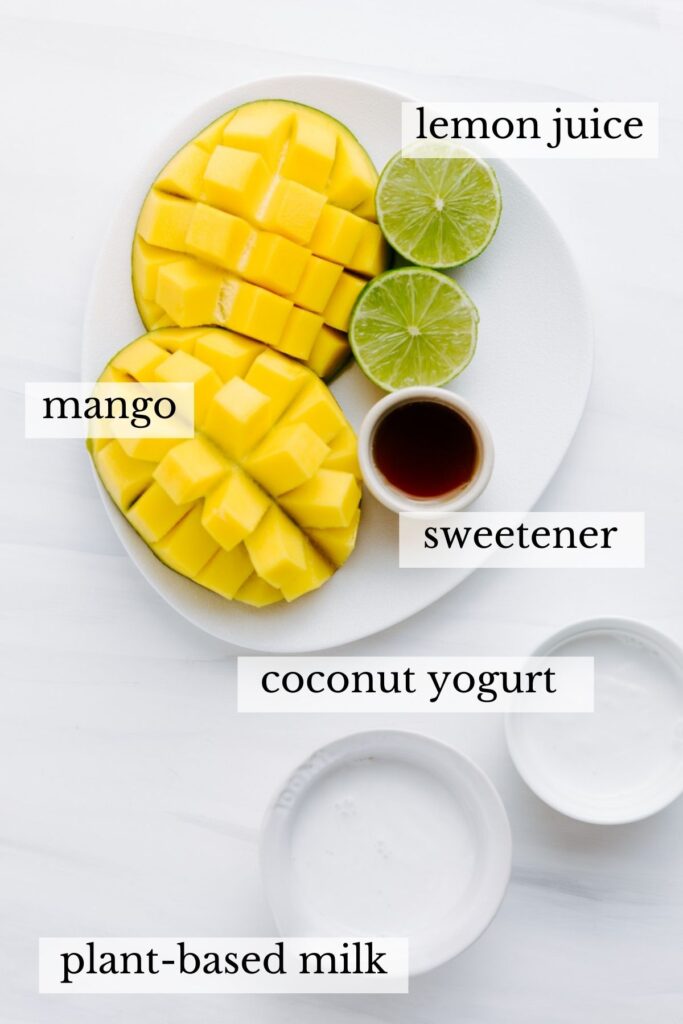 Ingredients for mango lassi on an oval white plate on a white backdrop