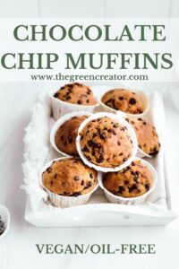 A white wooden tray with baked chocolate chip muffins placed on top of eachother in front of a white backdrop with pinterest text over the top image