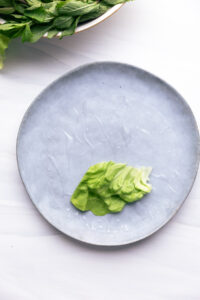 A blue plate with a wet sheet of rice paper and a lettuce leaf on the bottom part