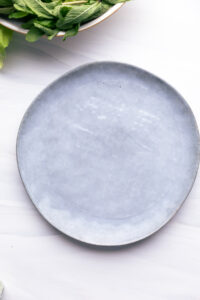 A blue plate with a wet sheet of rice paper on a white backdrop