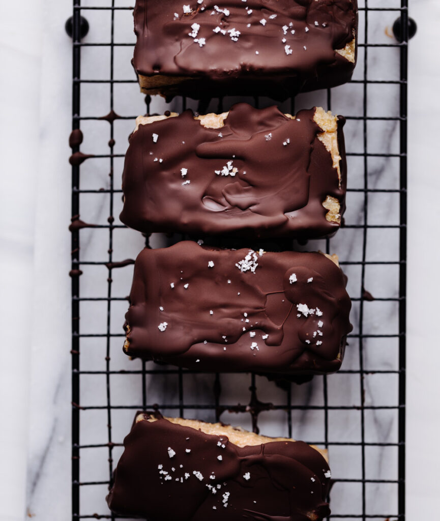 salted caramel chocolate bars sprinkled with salt on a small black cooling rack