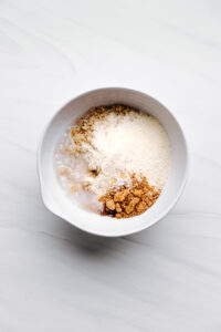 dry and wet ingredients for salted caramel bars in a white bowl on a white backdrop