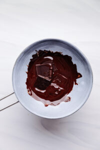 melted chocolate in a blue bowl on a white backdrop