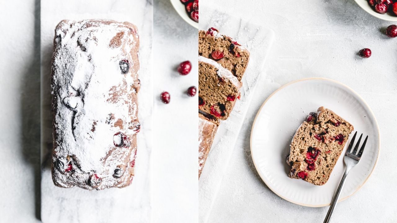 orange cranberry bread on white marble cuttingboard next to sliced cranberry orange bread on a white plate