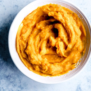 Pumpkin Puree in a white bowl on a blue backdrop