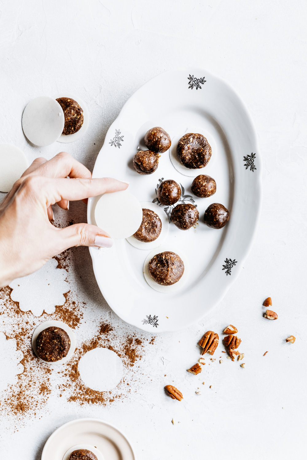 process making gingerbread bites on an oval white plate on a white backdrop and a hand holding a gingerbread