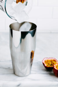 a silver colored cocktail shaker with ice cubes falling into it