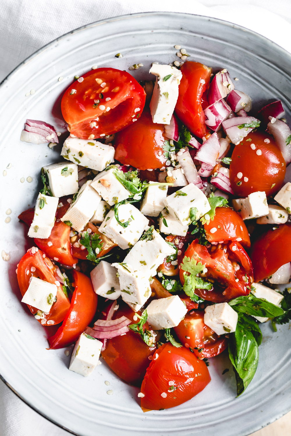 vegan feta cheese tomato salad in a blue bowl close up